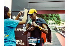 A triathlete approaches the finish line during the run segment of Ironman Rwanda 70.3 in Gisenyi, Rwanda, with athlete collecting his medal