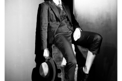 Black and white studio portrait with hat and suit styling